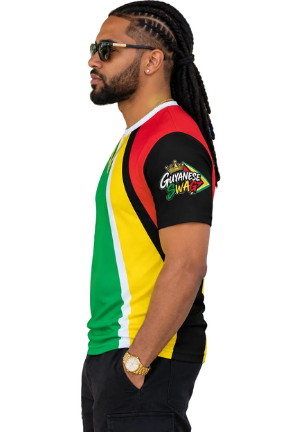 A man wearing a Guyanese flag-themed short-sleeve t-shirt with a 'WAVES' graphic on the sleeve, standing outdoors at a festival or event.